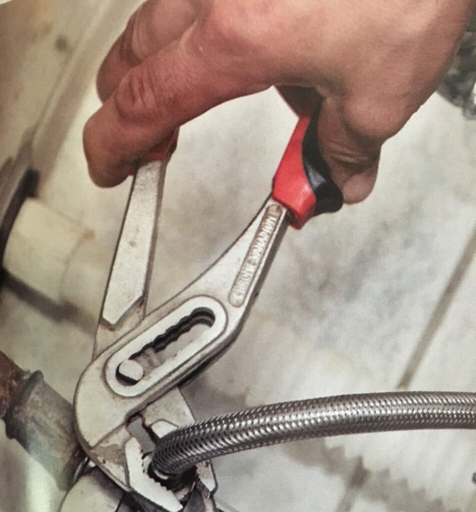 Close view of plumber's hands as they use a wrench to make a repair.