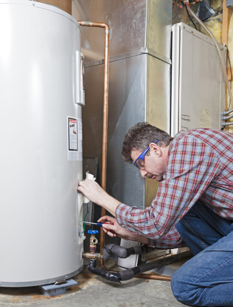 A plumber is performing maintenance on a residential water heater.