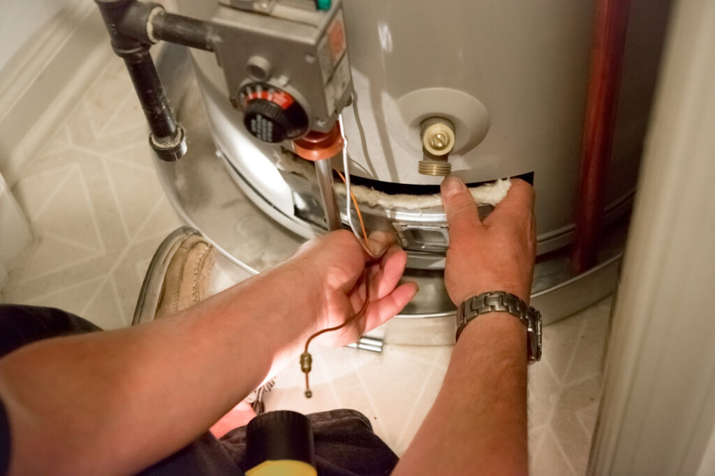 Close view of plumber's hands performing maintenance on a water heater.